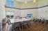 Bright and modern meeting room featuring expansive windows, chic decor, and ample seating with inspirational neon signage.