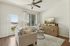 Bright and inviting living room with cozy sofa, stylish armchair, and sleek entertainment console, featuring large windows and a modern ceiling fan.