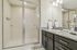 Contemporary bathroom with sleek glass-enclosed shower, elegant granite countertop, and modern lighting fixtures.