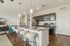 Modern kitchen with sleek countertops, stainless steel appliances, and stylish dining area, enhanced by elegant lighting.