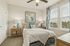 Bright and inviting bedroom featuring a cozy queen bed with elegant bedding, artistic wall art, and stylish blue accents.