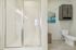 Bright, modern bathroom with a glass-enclosed shower, sleek cabinetry, and elegant tile flooring, highlighted by contemporary artwork.