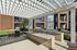 Chic outdoor lounge area with modern barbecue grills and stylish pergola in a vibrant apartment complex setting.