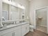 Modern bathroom with elegant dual sinks, spacious mirrored vanity, and an adjacent walk-in closet.