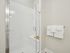 Bright, modern shower with sleek glass doors and pristine white tiles, accented by fresh, plush towels for a luxurious feel.