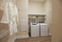 Modern laundry room with sleek washing and drying machines, ample shelving, and elegant wood flooring.