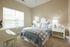 Bright and cozy bedroom with elegant decor, featuring a stylish checkered bedspread, matching pillows, and abundant natural light through large blinds-covered windows.
