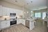 Modern open-plan kitchen and living area with sleek cabinetry, stainless steel appliances, and cozy seating under elegant pendant lighting.