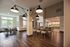 Elegant open dining and kitchen area with modern lighting, wooden floors, and large windows inviting natural light.