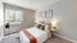 Bright bedroom with large window, cozy bedding, and neutral decor