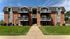Charming brick apartment building with classic gabled roofs and inviting balconies, set against a vibrant blue sky.