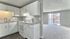Modern kitchen with sleek white cabinets and a bright open living space, showcasing a cozy and inviting apartment with a balcony view.