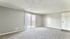 Spacious living area with plush carpet, bright natural light, and sliding glass doors leading to a private balcony or patio.