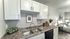 Charming kitchen with sleek white cabinets, modern double sink, and elegant brown countertop leading to a cozy living area with stylish decor.