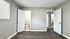 Bright and spacious bedroom featuring sleek wood flooring, neutral gray walls, and convenient access to a modern ensuite bathroom.