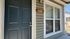 Inviting entrance of stylish apartment featuring a dark blue door and large windows, perfect for natural light.