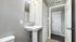 Bright and modern bathroom with sleek pedestal sink, large mirror, and ample storage in a contemporary apartment layout.