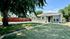 Charming single-story home with a well-maintained front lawn, vibrant red fence, and welcoming tree-lined path.