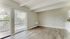 Bright and airy living room with sleek wooden flooring and large glass doors opening to a scenic balcony view.