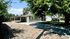 Charming single-story home with a covered carport and spacious gravel driveway, shaded by lush greenery.