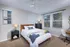 Bright and inviting bedroom with cozy double bed, stylish decor, and natural light streaming through two large windows.