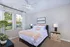 Bright and inviting bedroom with elegant decor, featuring a cozy bed with luxurious linens, large windows offering natural light, and stylish bedside lamps.