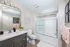 Modern bathroom with sleek vanity, elegant lighting, framed artwork, and a pristine glass shower enclosure.
