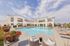 Luxurious apartment complex featuring a sparkling pool, elegant lounge chairs, and vibrant garden with a modern architectural backdrop.Amenity building located at 1800 Santa Carolina Road in Chula Vista, California.