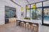 Modern leasing center with sleek design featuring a stylish bar area, yellow pendant lights, and a vibrant indoor garden, offering a view of the outdoor pool area.Amenity building located at 1800 Santa Carolina Road in Chula Vista, California.