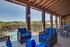 Charming outdoor patio with cozy seating, offering stunning views of a lush palm-lined pool area.