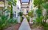 Charming apartment complex entrance with lush greenery and inviting pathways, perfect for serene living.