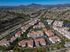 Scenic aerial view of a sprawling residential complex with red-roofed buildings, surrounded by lush greenery and a vibrant community setting with mountain backdrop.