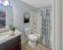 Bathroom featuring bathtub with shower curtain, toilet, and granite-top vanity at Winchester Arms apartments in Dover, New Hampshire