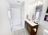 Well-lit bathroom at Grassfields Commons in Dracut, Massachusetts featuring a spacious vanity with storage, large mirror, and clean, neutral finishes