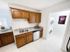 Functional kitchen space at Grassfields Commons in Dracut, Massachusetts featuring ample cabinetry, a convenient sink area, and direct access to an in-unit washer and dryer for everyday ease
