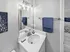 Bathroom with modern vanity, large mirror, bright lighting, and built-in storage shelving at Westgate Arms in Salem, New Hampshire