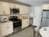Updated apartment kitchen with light cabinetry, stainless steel appliances, tile backsplash, and wood-style flooring