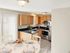 Kitchen with stainless steel appliances, light wood cabinetry, and adjacent dining area at Meadowbrook Village in Gardner, Massachusetts