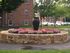 Outside court yard water fountain and flowers near parking lot and buildings