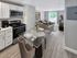Contemporary open-plan kitchen and living room featuring sleek appliances, elegant dining area, and bright natural light through large sliding doors.