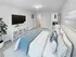 Elegant bedroom with plush carpeting, featuring a luxurious bed with colorful pillows, stylish entertainment console, and a spacious closet.