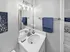bathroom showcasing modern fixtures, a sleek white vanity, and plush blue accents, creating an inviting and fresh atmosphere.