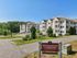 Entrance view of Grassfields Commons in Dracut, Massachusetts with landscaped grounds, residential buildings, and community signage