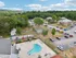 Aerial view of Manchester Gardens in Manchester, New Hampshire showing a swimming pool, surrounding patio area, parking, and a fenced sports court within the community
