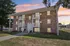 Apartment building at Manchester Gardens in Manchester, New Hampshire featuring a brick exterior, private balconies, and a central entrance with steps and railings