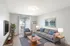 Living room with large window and sliding door, wall-mounted air conditioning unit, and open layout leading to adjacent spaces