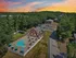 Charming aerial view of an apartment community showcasing a serene pool area surrounded by lush greenery, vibrant lounge umbrellas at Derry Country Club Estates in Derry, NH.