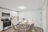 Stylish open kitchen and dining space with crisp white cabinetry, stainless steel appliances, and a cozy round dining table setup at Derry Country Club Estates in Derry, NH.