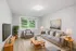 Comfortably styled living room with soft neutral tones, large picture window, and mid-century inspired furnishings at Derry Country Club Estates in Derry, NH