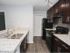 Kitchen with white granite counters, dark cabinets, wood flooring, track lighting